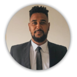 Foto do Arthur. Ele tem barba, veste terno, sorri e olha diretamente para a câmera.