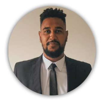 imagem circular. Foto do ARTHUR: um homem negro. Arthur usa barba. Está vestido com terno e gravata. Arthur sorri na foto.