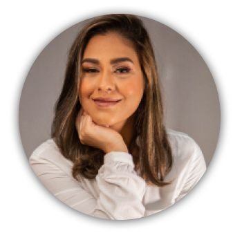 imagem circular. Bianca Kremer é uma mulher jovem, branca. está com cabelo solto e veste blusa branca. Está com a mão no queixo e sorrindo.